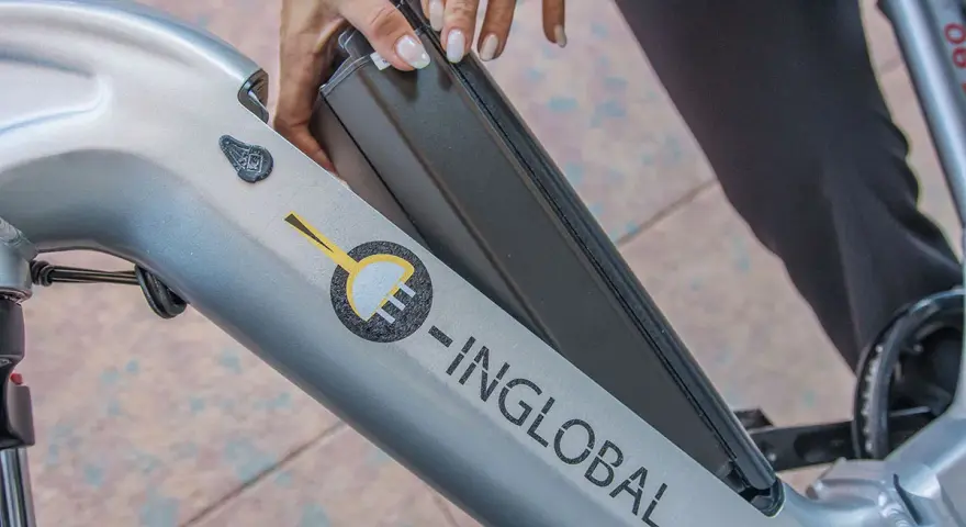Mani che inseriscono la batteria in una bici elettrica. La durata della batteria di una bici elettrica è fondamentale per l'autonomia.