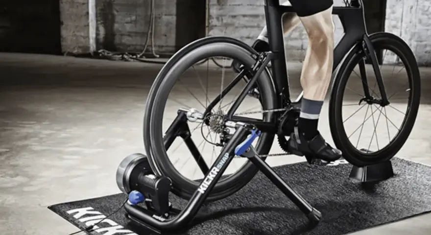 A person is engaged in indoor cycling training on a trainer in a gritty, industrial-style room.