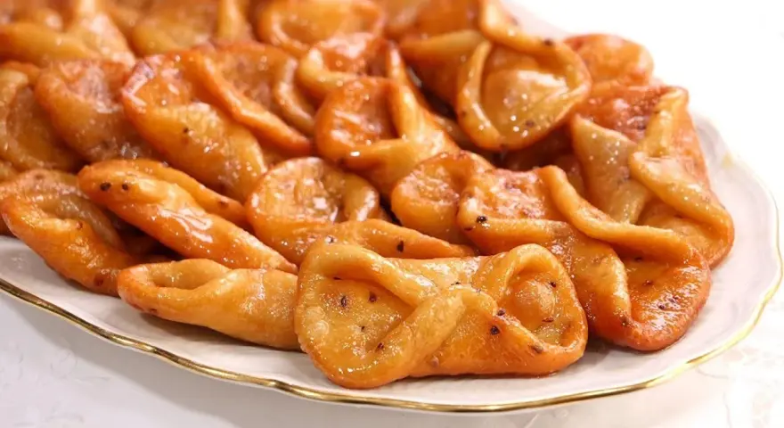 Plato de pestiños antiguos, dorados y brillantes, con un glaseado que los hace irresistibles. Perfectos para acompañar un café.