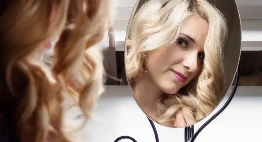 Piękna blondynka z burzą loków, odbijająca się w lustrze. To idealny sposób na loki przez noc.