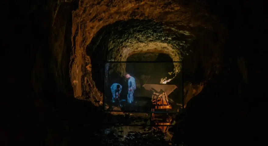 W jaskini wyświetlany jest film, na którym widać dwie postacie w pasiaste ubrania. Czy to osówka czy włodarz?