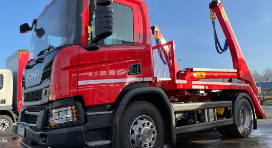 Czerwony hakowiec Scania gotowy do akcji. Sprawdź, jaka jest utylizacja gruzu cena za tonę, by pozbyć się odpadów budowlanych.