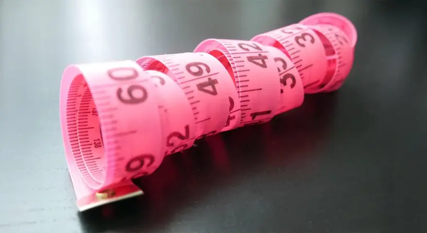 Różowa taśma miernicza zwinięta w spirale, z widocznymi numerami, jak na elefanten tabela rozmiarów.