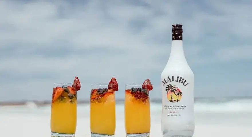 Letnie drinki z malibu na plaży, ozdobione truskawkami i borówkami. Idealne na upalne dni.