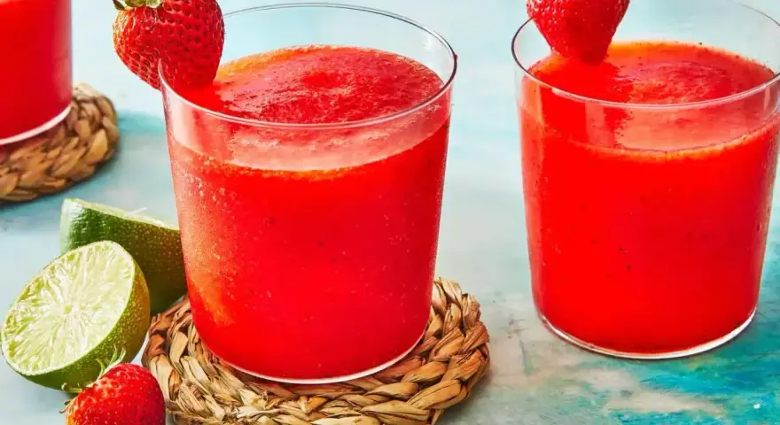 Orzeźwiający drink z truskawkami, ozdobiony świeżymi owocami i limonką, idealny na upalne dni.