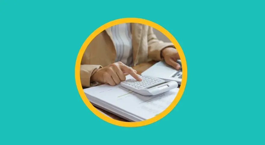 Une personne utilise une calculatrice sur des documents pour apprendre comment payer moins d'impôts.