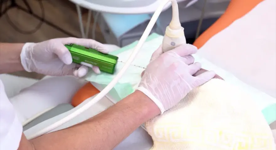 Arzt führt eine Brust-Biopsie mit einem speziellen Gerät durch. Hände in Handschuhen halten die Nadel und den Ultraschallkopf.