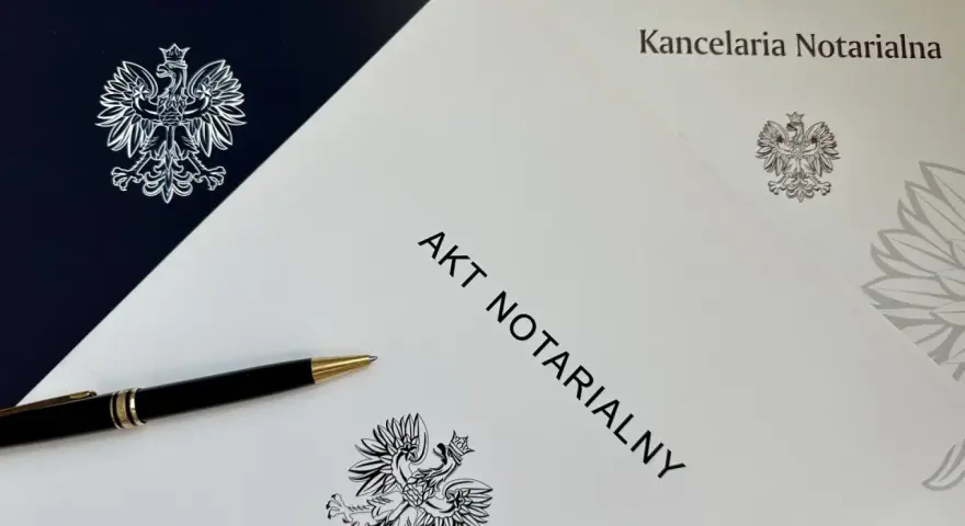 Akt notarialny i długopis na tle dokumentów z godłem Polski.