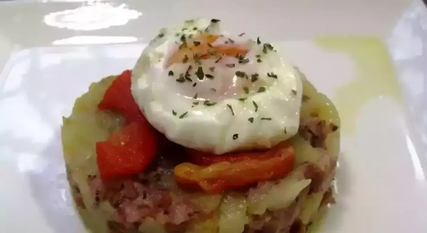 Delicioso timbal de patata con huevo escalfado y pimientos rojos, un plato que te hará chuparte los dedos.