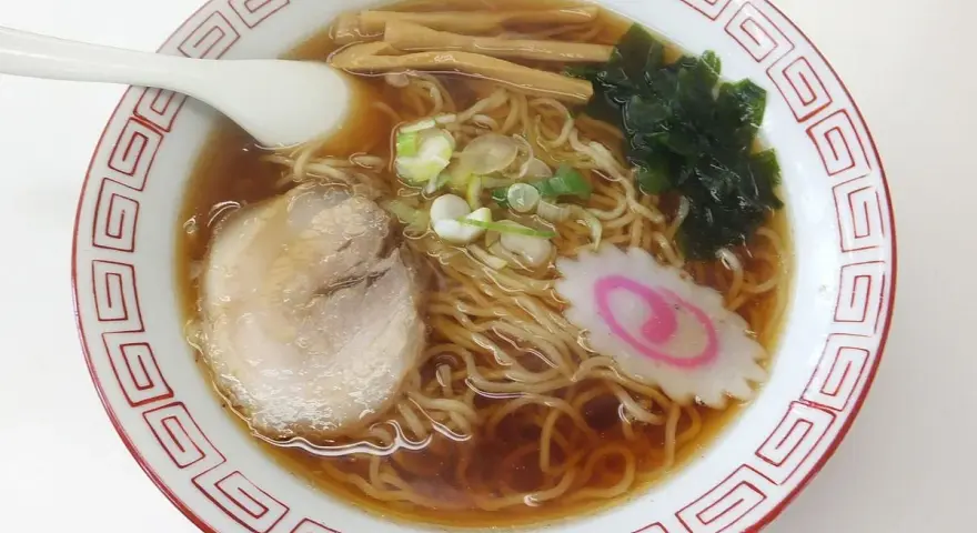 Miseczka aromatycznego ramenu, dania, którego **ramen skąd pochodzi** jest z Japonii. Widać makaron, plastry mięsa, nori, bambus i narutomaki.