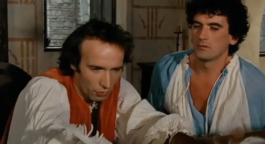 Due uomini in abiti d'epoca, uno scrive con una penna d'oca, in una scena che promette un film comico.