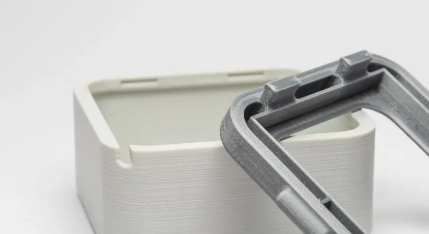 Close-up of a 3D-printed white box and a grey lid, showcasing the intricate snap fit joints designed for easy assembly.
