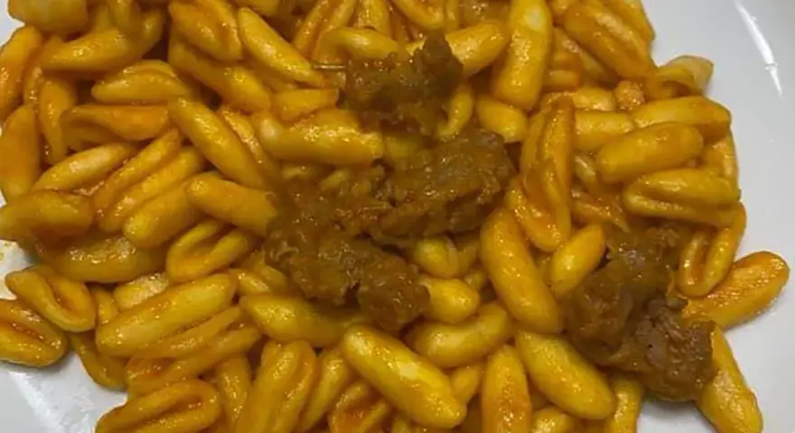 Un piatto invitante di gnocchetti alla campidanese, conditi con un sugo ricco e pezzetti di carne saporita.