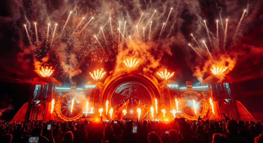 Spektakularny pokaz fajerwerków i płomieni na scenie podczas festiwalu Sunrise Festival 2026. Tłum ludzi z telefonami wzniesionymi ku górze.