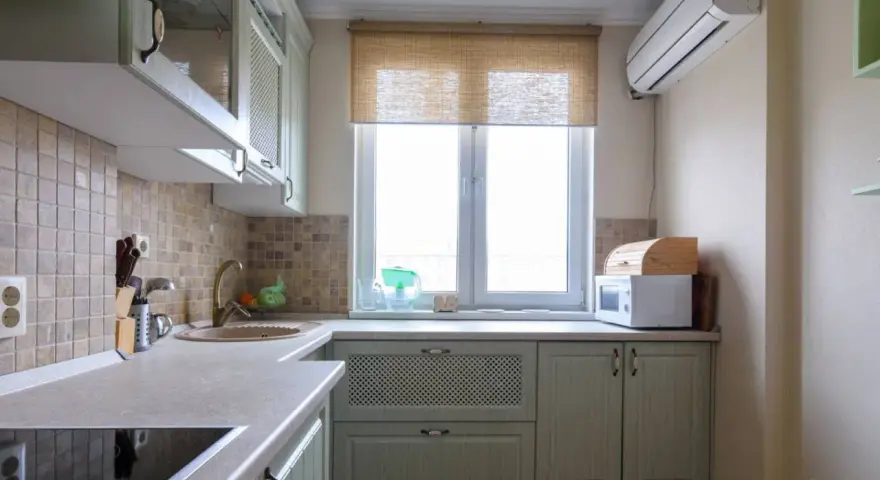 Cortinas de cocina de bambú sobre ventana, con microondas y panera de madera.