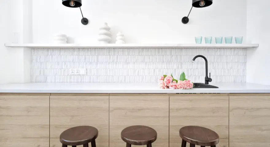 Nowoczesna kuchnia z drewnianymi frontami, białym blatem i mozaikową ścianą nad blatem. Idealna do poszukiwania innych opcji wykończenia ścian w kuchni.