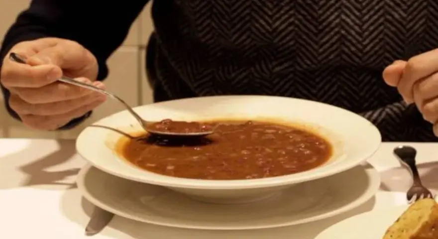 Persona prueba una cucharada de una humeante olla podrida, un plato reconfortante y tradicional.