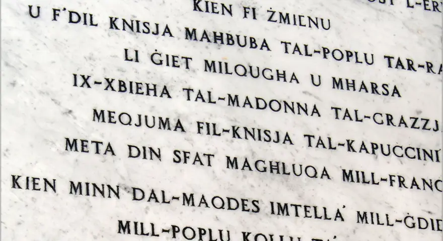 Napis na marmurze w języku maltańskim. Tekst opowiada historię o kościele i jego znaczeniu dla ludzi.