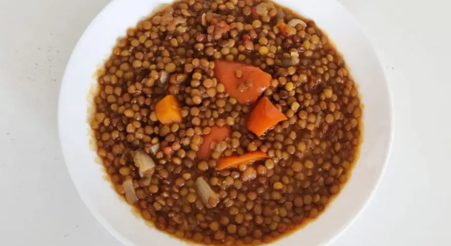 Un plato de lentejas guisadas con zanahoria y cebolla, cocinadas en olla express. Un plato reconfortante y rápido.