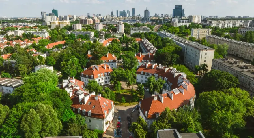 Zielony Żoliborz Oficerski z charakterystyczną architekturą i panoramą miasta w tle.