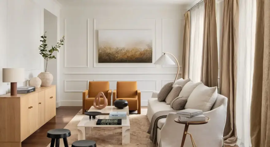 Elegante salón con salones con molduras en paredes, sofá blanco, sillones ocre y mesa de centro de mármol.
