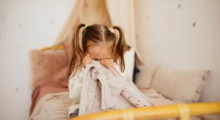 Kleines Kind mit Zöpfen versteckt sich unter einer Decke, weil es Angst vor Monstern hat.