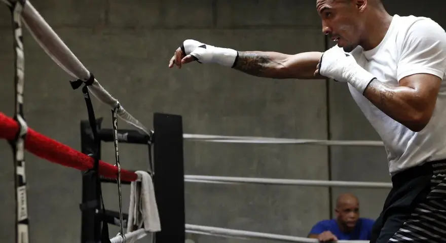 Un boxeur s'entraîne en shadow boxing dans un ring, concentré sur ses mouvements.