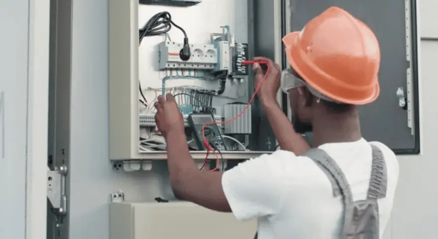 Elektryk w kasku sprawdza instalację fotowoltaiczną. Dowiedz się, jak obniżyć napięcie w sieci fotowoltaika.