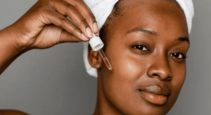 A woman applies a serum with peptides for acne, a step in her skincare routine.