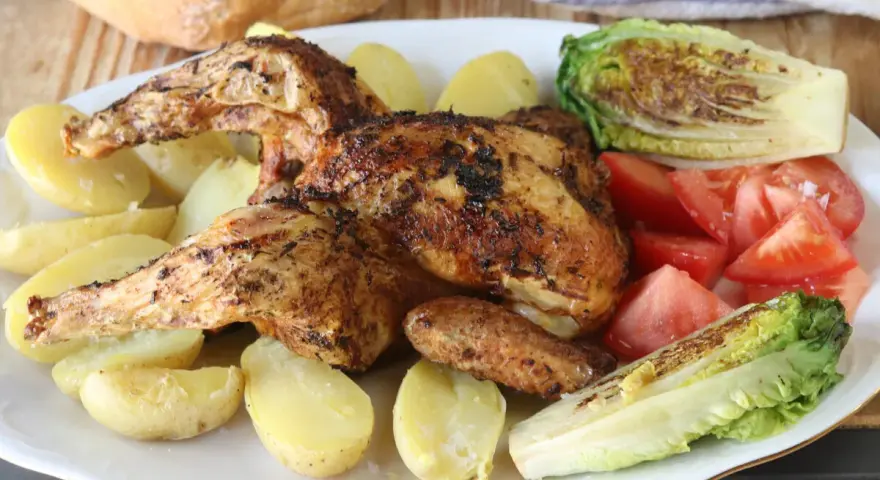 Pollo a la brasa jugoso y dorado, acompañado de papas amarillas, tomates frescos y lechuga a la parrilla. Un festín para los sentidos.
