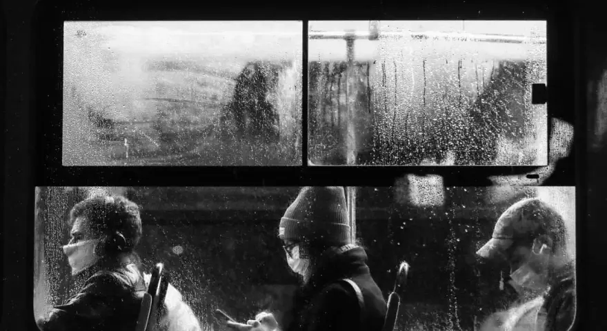 Trzej polscy fotografowie uchwycili deszczowy dzień w transporcie publicznym. Ludzie w maskach patrzą przez zaparowane okno.