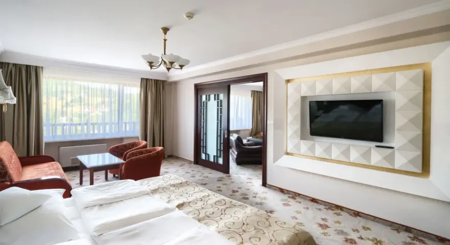 Wnętrze pokoju hotelowego z łóżkiem, kanapą i fotelem. Warto sprawdzić, ile pokoi ma Hotel Gołębiewski w Wiśle, by wybrać idealny dla siebie.