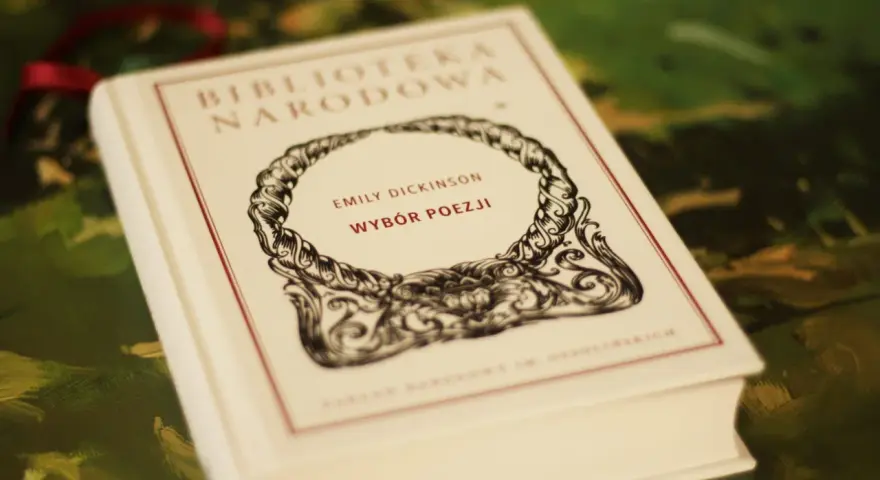 Biała księga z napisem "Emily Dickinson Wybór Poezji" w ozdobnej ramce.