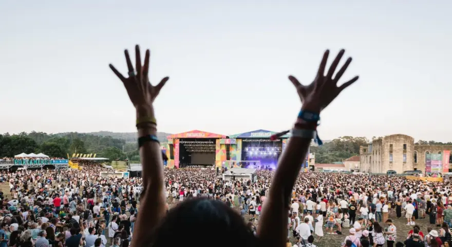 Manos alzadas en el festival Portamérica, disfrutando de la música y la multitud bajo un cielo despejado.