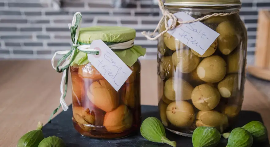 Zwei Gläser mit eingelegten unreifen Feigen, eines in Essig, das andere in Salzlake. Perfekt für unreife Feigen Rezepte.