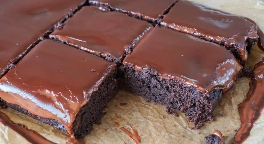 Saftige, vegane Brownies mit glänzendem Schokoladenguss, in Quadrate geschnitten. Ein Genuss für alle Schokoladenfans!