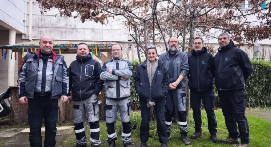 Une équipe de gardiens d'immeuble pose devant un bâtiment, peut-être pour célébrer une nouvelle loi les concernant.