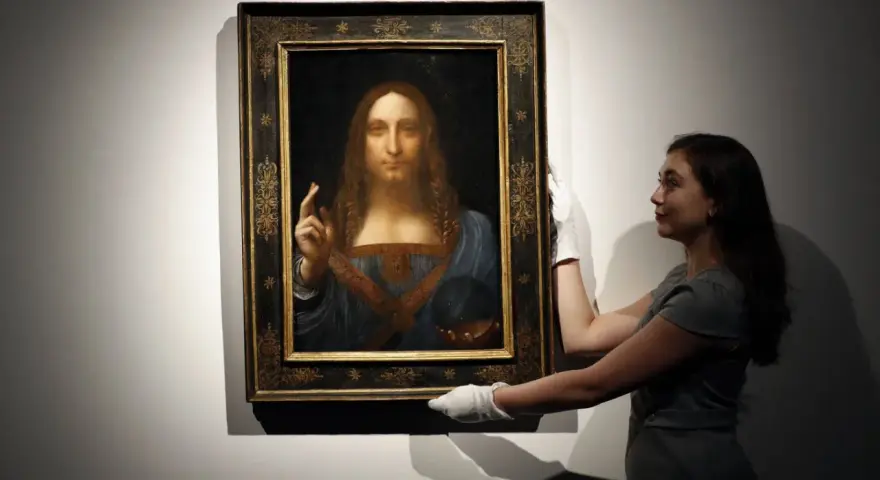 En kvinna med vita handskar hanterar den berömda tavlan "Salvator Mundi", ibland kallad "Mona Lisa tavla" av misstag.
