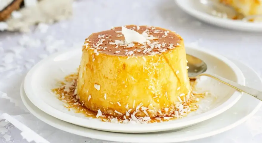 Delicioso flan de coco, cubierto con caramelo dorado y coco rallado, listo para disfrutar.
