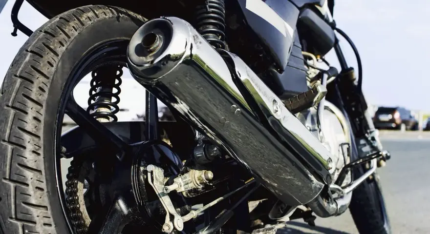 Detalle de la rueda trasera y el escape cromado de una motocicleta. Si te preguntas cuanto cuesta homologar un escape, este podría ser el tuyo.