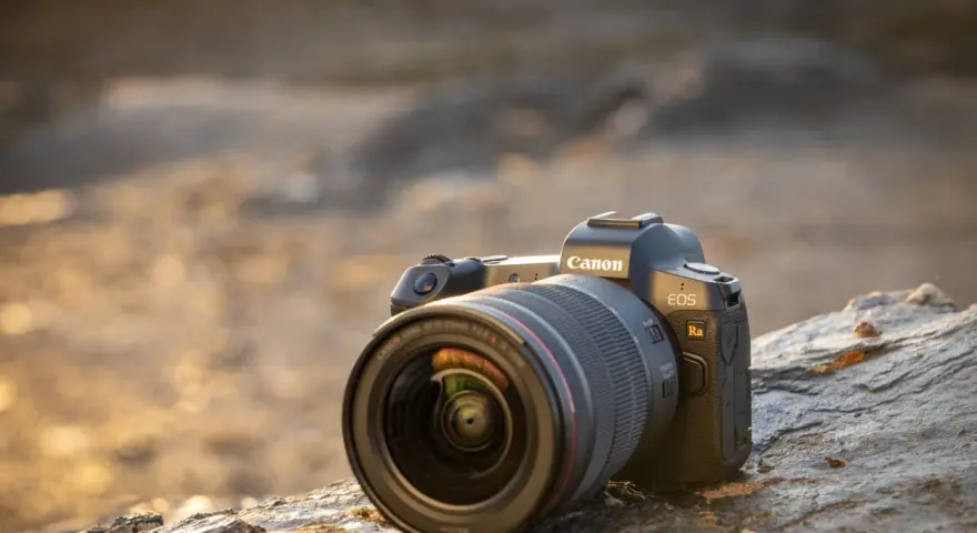 Aparat Canon EOS Ra z obiektywem RF 15-35mm f/2.8L IS USM leży na kamieniu.