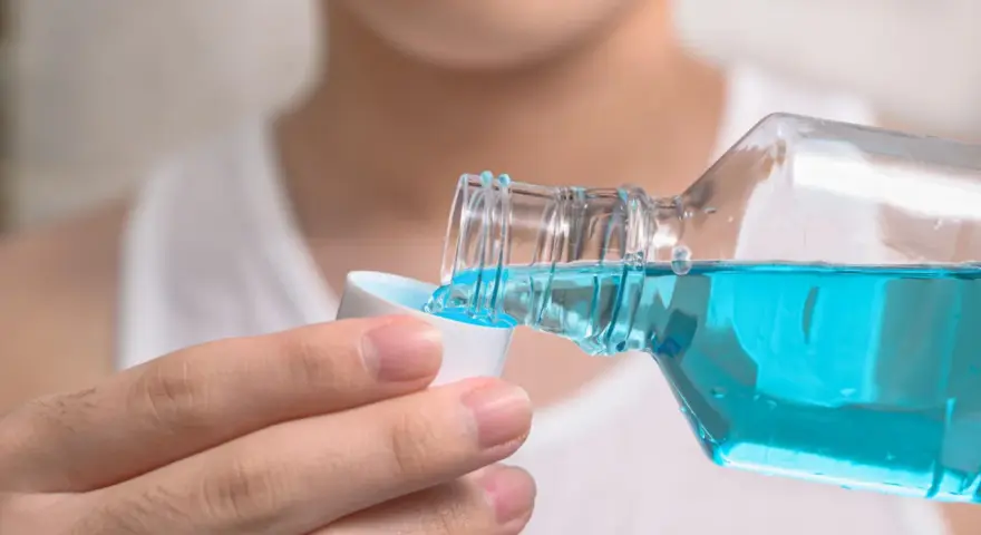 Niebieski płyn do płukania jamy ustnej, z butelki przelewany do nakrętki. Idealny do odświeżenia oddechu.