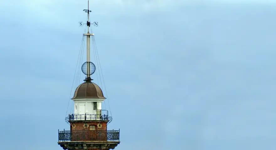 Szczyt latarni morskiej w Gdańsku z wiatrowskazem i kulistą ozdobą.