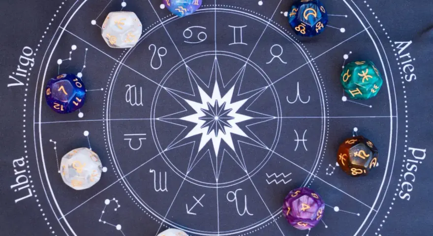 Kolorowe kostki z symbolami zodiaku i liczbami, leżące na tle z kołem horoskopowym. Każda liczba w numerologii ma swoje znaczenie.