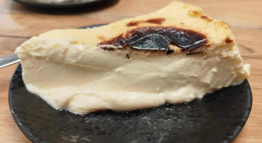 Rebanada cremosa de pastel vasco, con su característico exterior tostado y un interior suave y delicioso.
