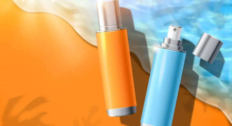 Due flaconi spray, uno arancione e uno azzurro, sulla sabbia dorata con onde marine. Protezione solare con butyl methoxydibenzoylmethane.