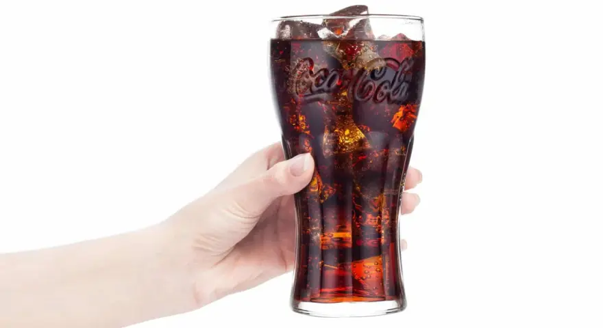 Hand hält Glas mit eiskalter Cola. Frage: Ist Cola in der Schwangerschaft erlaubt?