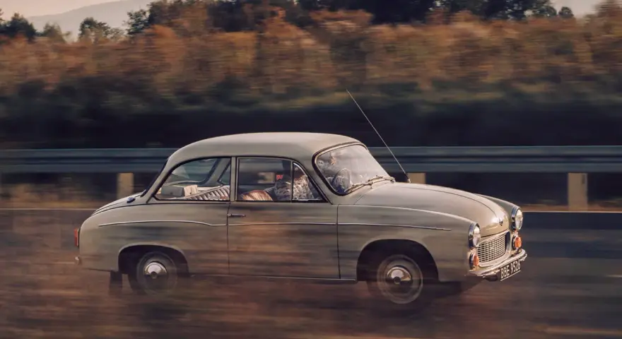 Klasyczny Syrena 105 na drodze, uchwycony w dynamicznym ujęciu panning shot.