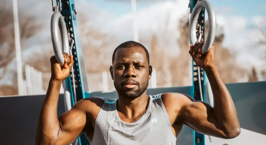 Un homme musclé s'entraîne avec des anneaux de street workout maison.