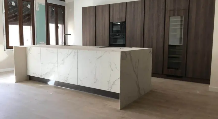 Isla de cocina moderna con encimera de mármol y armarios oscuros. Se aprecian las medidas de los muebles de cocina en el diseño.